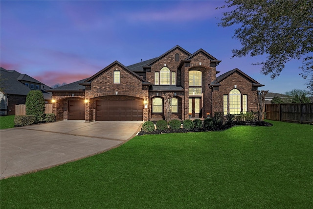 view of front of property with an attached garage, fence, brick siding, and a yard