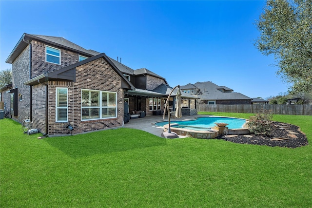 back of property with a pool with connected hot tub, a patio, a fenced backyard, a yard, and brick siding