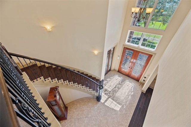 entrance foyer featuring a notable chandelier, french doors, stairs, and a towering ceiling