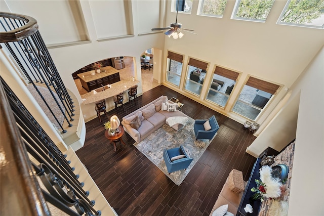 living room featuring stairway, a ceiling fan, a towering ceiling, and wood finished floors