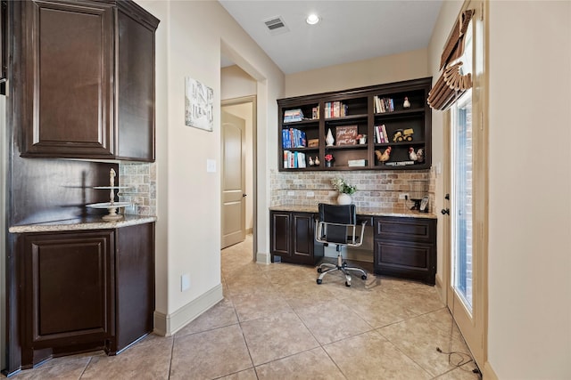 office featuring visible vents, plenty of natural light, built in desk, light tile patterned floors, and baseboards