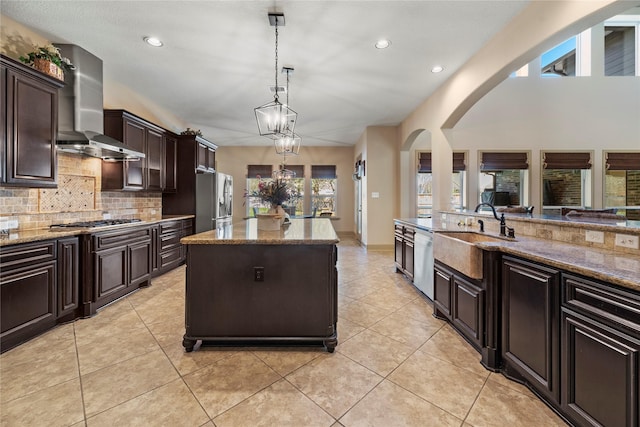 kitchen with light stone counters, appliances with stainless steel finishes, tasteful backsplash, and wall chimney exhaust hood