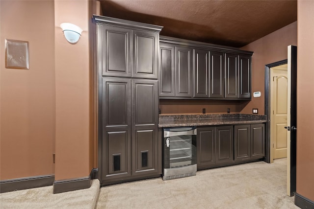 bar featuring beverage cooler, light carpet, and a bar