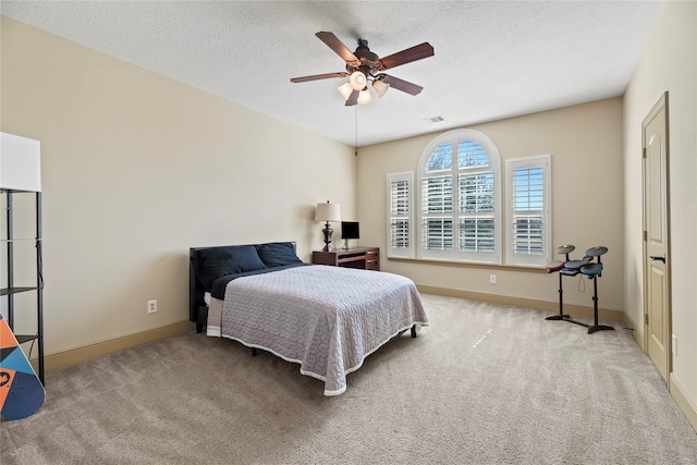 carpeted bedroom featuring ceiling fan, baseboards, visible vents, and a textured ceiling