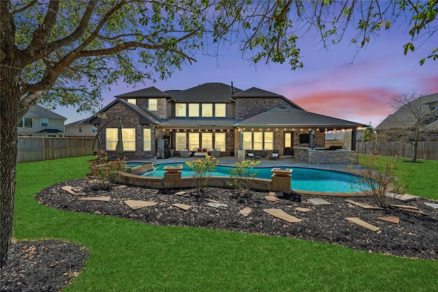 rear view of property featuring a yard, brick siding, outdoor lounge area, and a fenced backyard