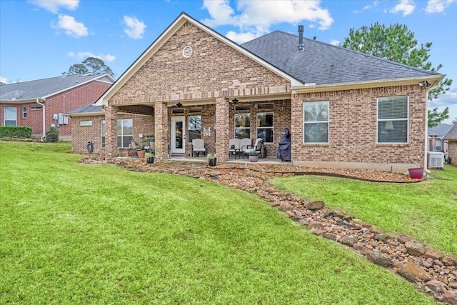 rear view of property with brick siding, a shingled roof, ceiling fan, a yard, and a patio