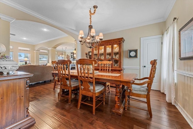 dining room with dark wood finished floors, arched walkways, and ornamental molding