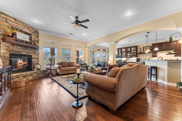 living area with a fireplace, a textured ceiling, dark wood-type flooring, and ornate columns