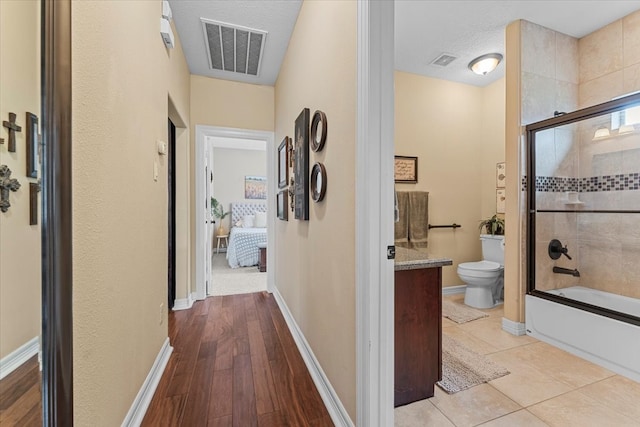 hall featuring tile patterned flooring, visible vents, and baseboards