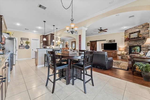 dining space featuring visible vents, arched walkways, light tile patterned flooring, and ceiling fan with notable chandelier