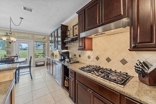 kitchen with visible vents, under cabinet range hood, stainless steel gas stovetop, light tile patterned flooring, and crown molding