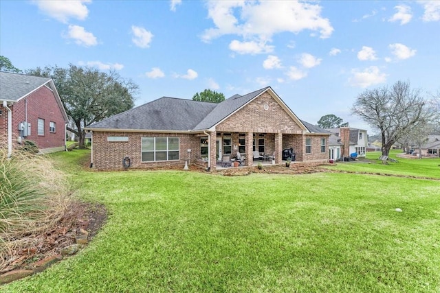 back of property featuring a patio area, brick siding, a lawn, and a shingled roof