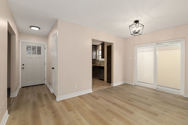 unfurnished dining area with light wood-style floors, baseboards, and a chandelier