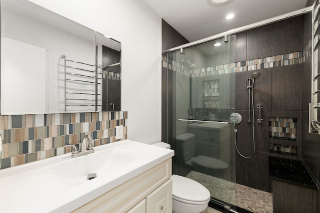 bathroom with vanity, a shower stall, toilet, and tasteful backsplash