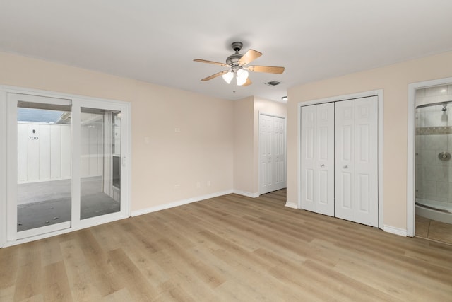 unfurnished bedroom featuring connected bathroom, baseboards, light wood-type flooring, and multiple closets