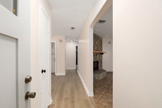 hallway with visible vents, baseboards, and light wood finished floors