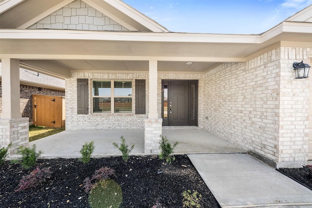 property entrance featuring a porch and brick siding