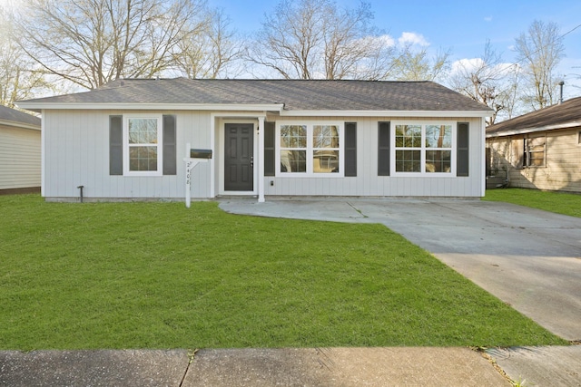 ranch-style home with a shingled roof and a front lawn