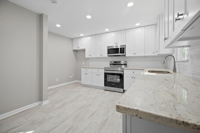 kitchen featuring light stone counters, tasteful backsplash, appliances with stainless steel finishes, and a sink