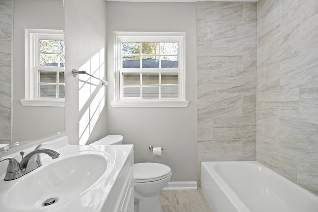 bathroom with vanity, toilet, a healthy amount of sunlight, and baseboards