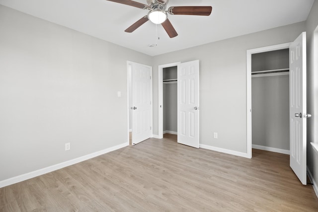 unfurnished bedroom featuring a ceiling fan, baseboards, light wood-type flooring, and two closets