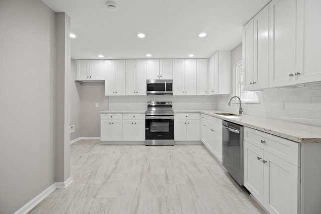 kitchen featuring white cabinets, backsplash, appliances with stainless steel finishes, and a sink