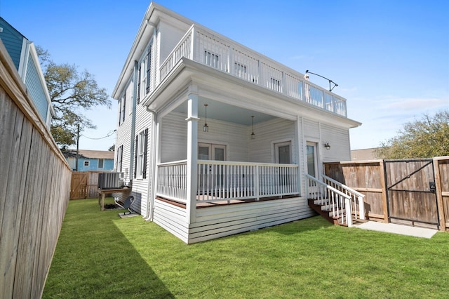 back of house featuring a yard, central air condition unit, a balcony, and a fenced backyard