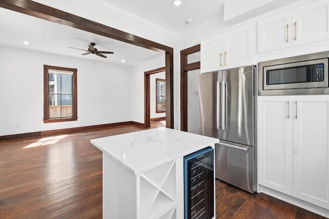 kitchen with dark wood-type flooring, baseboards, light stone countertops, beverage cooler, and appliances with stainless steel finishes