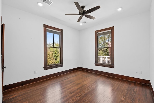 empty room with dark wood-style floors, visible vents, recessed lighting, and baseboards