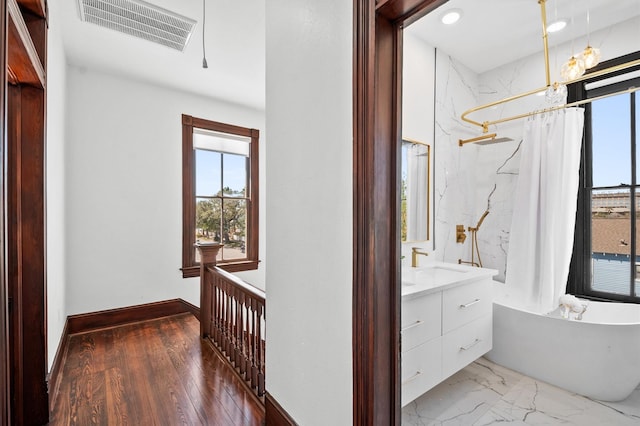 corridor with a sink, visible vents, baseboards, and marble finish floor