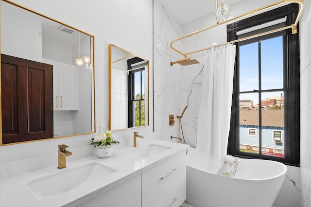 bathroom featuring double vanity, a soaking tub, visible vents, and a sink