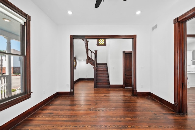 empty room with stairs, plenty of natural light, wood finished floors, and baseboards