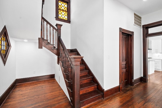 staircase featuring visible vents, wood-type flooring, and baseboards