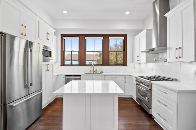 kitchen with a sink, premium appliances, wall chimney exhaust hood, and dark wood finished floors