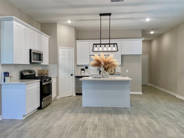 kitchen featuring light wood finished floors, white cabinetry, stainless steel appliances, and light countertops