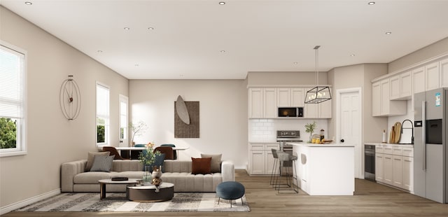 living room with recessed lighting, a healthy amount of sunlight, light wood-style flooring, and baseboards