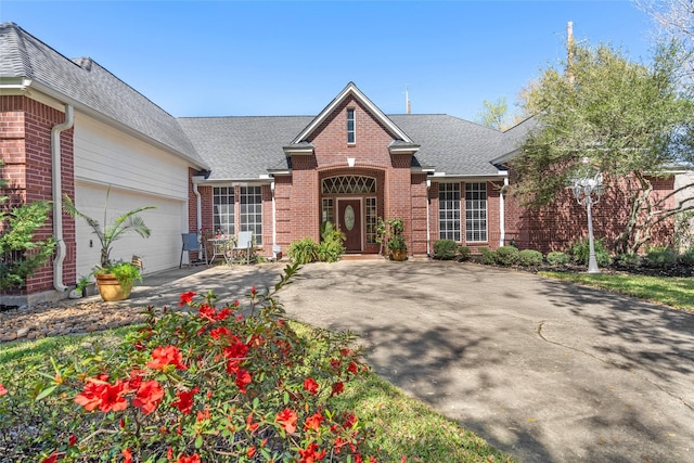 traditional home with driveway, brick siding, roof with shingles, and an attached garage