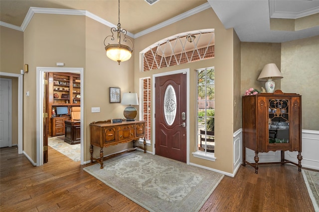 foyer with baseboards, a high ceiling, wood finished floors, and ornamental molding