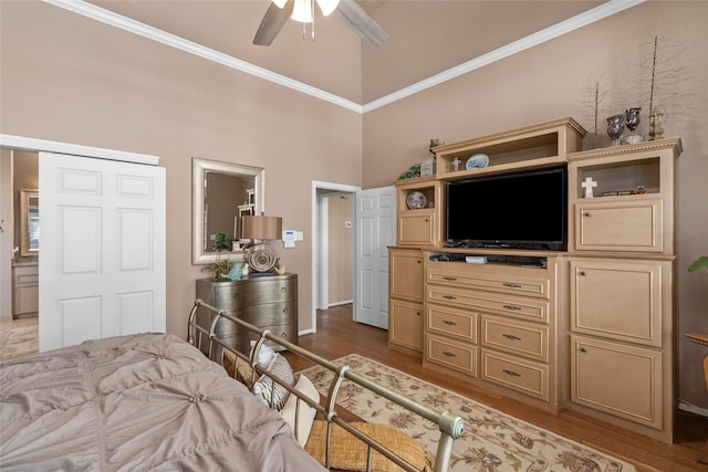 bedroom with a towering ceiling, wood finished floors, crown molding, and ceiling fan