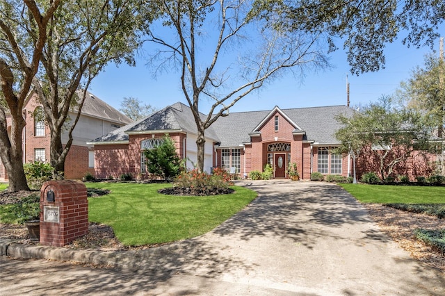 view of front of home featuring aphalt driveway, a garage, brick siding, and a front yard