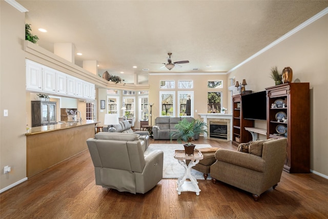 living area featuring a ceiling fan, wood finished floors, a high end fireplace, crown molding, and baseboards