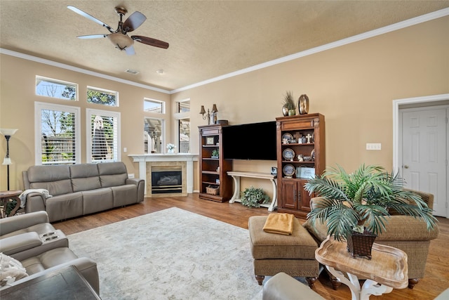 living area featuring a textured ceiling, ceiling fan, wood finished floors, and ornamental molding