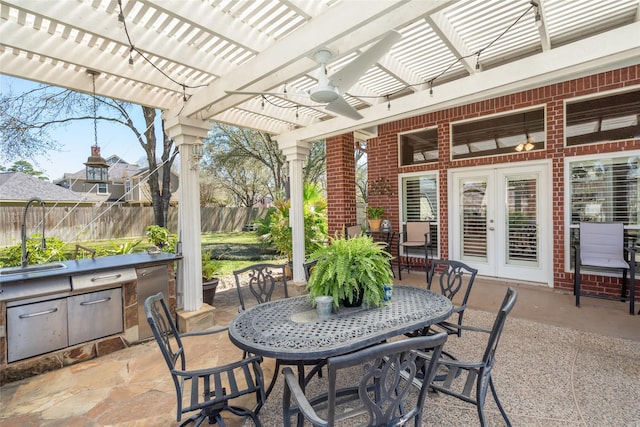 view of patio / terrace with fence, exterior kitchen, outdoor dining area, a pergola, and a sink