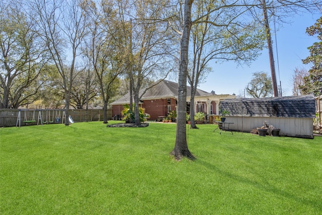 view of yard featuring an outbuilding, a storage unit, and fence