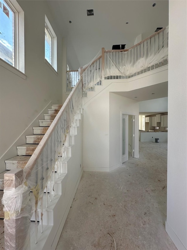 stairway featuring baseboards and a towering ceiling