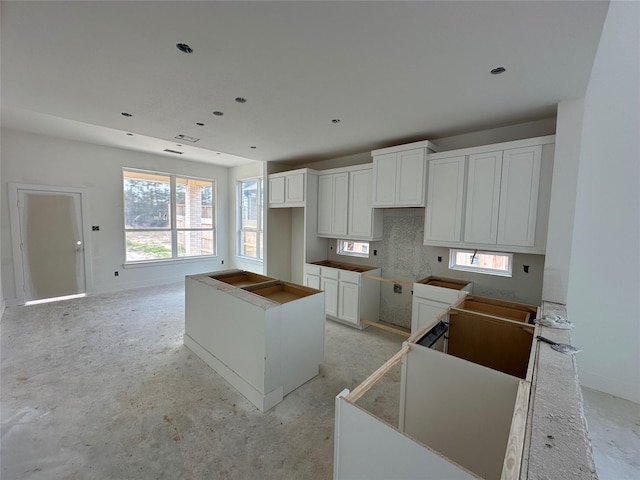 kitchen with white cabinets, a kitchen island, and baseboards