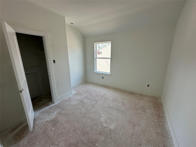 unfurnished bedroom with lofted ceiling and baseboards