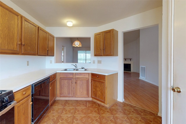 kitchen with brown cabinetry, visible vents, a sink, black appliances, and light countertops