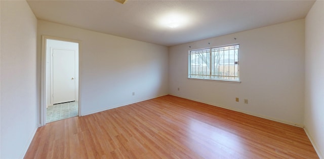 unfurnished room with baseboards and light wood-style floors