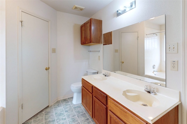 bathroom featuring double vanity, visible vents, toilet, and a sink